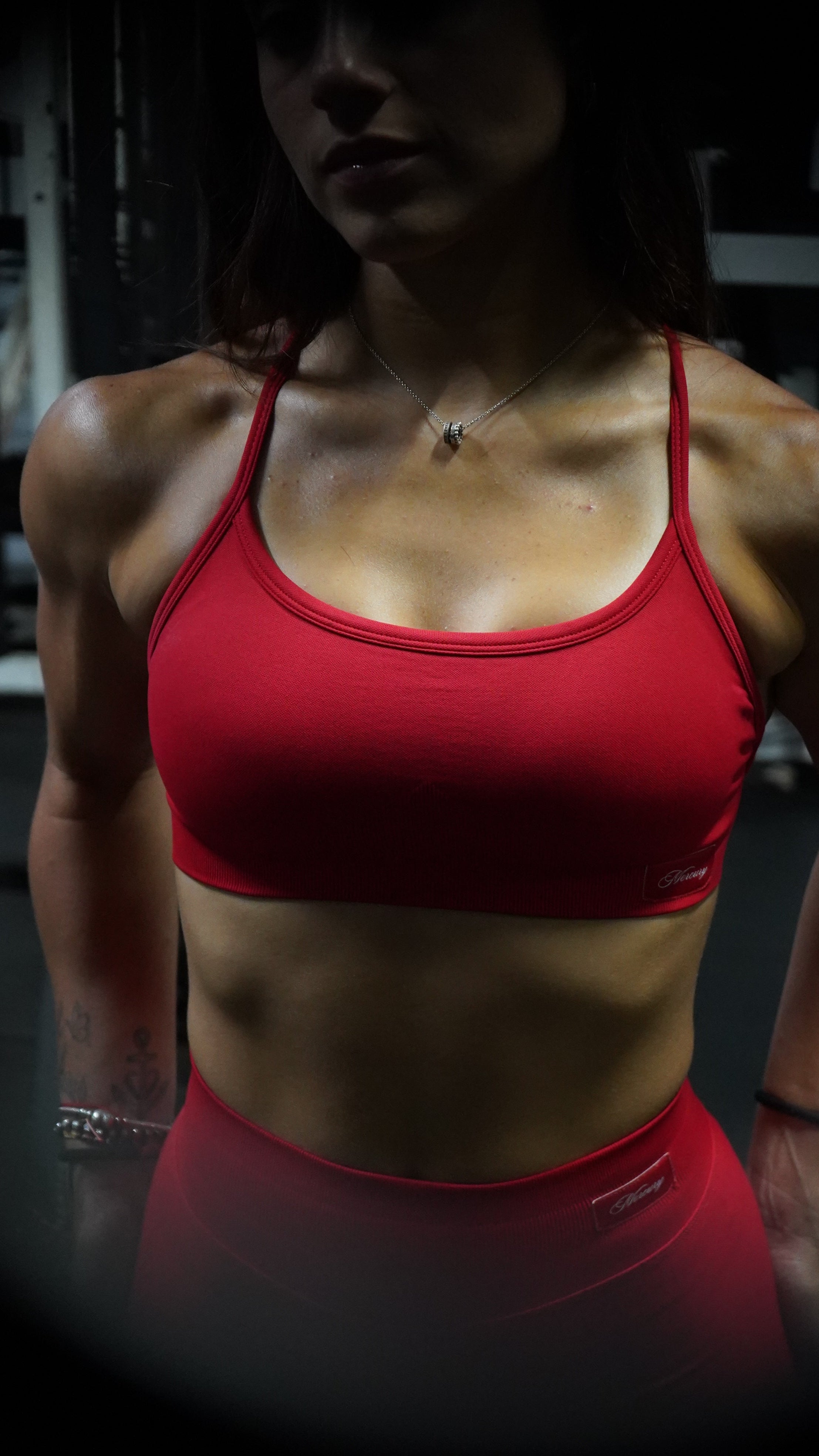 Person wearing a red sports bra in a dimly lit room